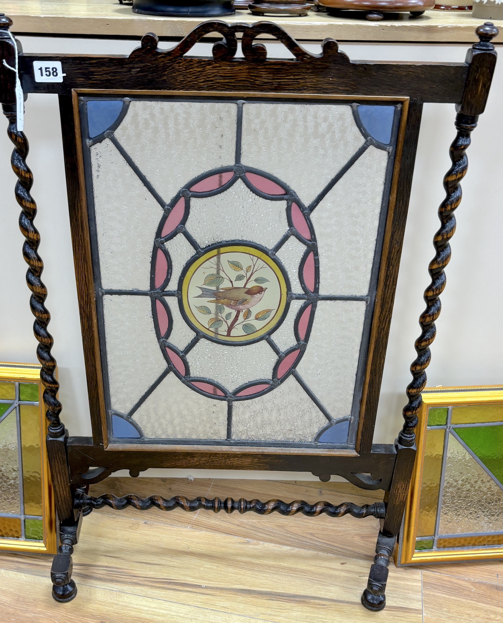 An early 20th century stained glass oak firescreen, height 84cm together with a pair of Art Deco style stained glass panels